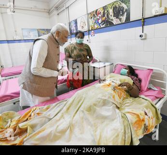 Morbi, Indien. 01.. November 2022. Der indische Premierminister Narendra Modi, links, besucht ein Opfer des Zusammenbruchs der Fußgängerbrücke von Morbi im öffentlichen Krankenhaus, 1. November 2022, in Morbi, Gujarat, Indien. Die kürzlich renovierte Fußgängerbrücke aus der viktorianischen Zeit brach zusammen und tötete am 30.. Oktober mindestens 135 Menschen. Kredit: Presseinformationsbüro/PIB Foto/Alamy Live Nachrichten Stockfoto