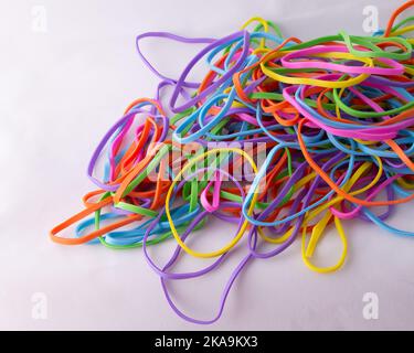 Ein Haufen von Neon-mehrfarbigen Regenbogen-Gummibändern auf weißem Hintergrund mit Kopierraum Stockfoto