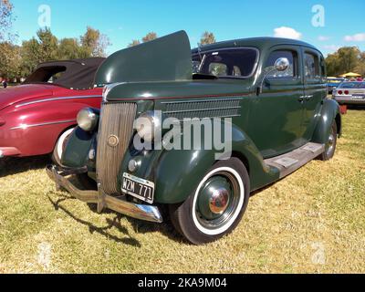 Chascomus, Argentinien - 9. Apr 2022: Vintage Green Ford Model 48 V8 Fordor Limousine 1936 auf dem Land. Natur, Gras, Bäume. Oldtimer-Show. Stockfoto