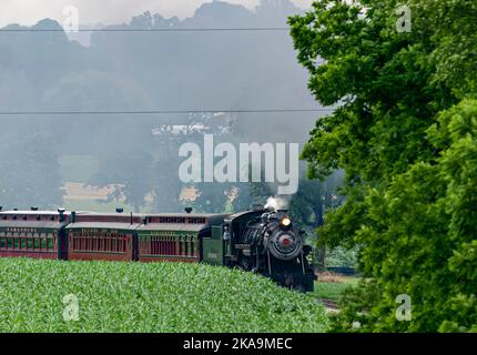 Ronks, Pennsylvania, 18. Juni 2021 - Blick auf einen restaurierten Dampfzug, der sich mit Rauch und Dampf einer Kurve nähert Stockfoto