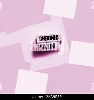 Chronische Schmerzwörter auf Holzblöcken auf Rosa mit Copyspace. Gesundheitskonzept Stockfoto