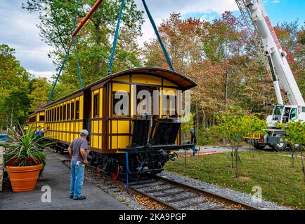 Elizabethtown, Pennsylvania, 7. Oktober 2020 - Installation eines neuen gelben Passagierfahrgastes, der von einem Kran angehoben wird, um an einem Herbsttag auf einem Eisenbahntrasse auf Zugmaschinen zu montieren Stockfoto