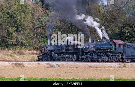 Ein Blick auf zwei Dampfmaschinen, Rauchschwaden und Dampfaufwärmung an einem sonnigen Tag nebeneinander Stockfoto