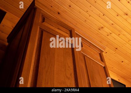 Holzschrank in einem Raum mit Holzwänden, Holzinterieur im Haus, Blick auf die Decke und Schrank von unten nach oben Stockfoto