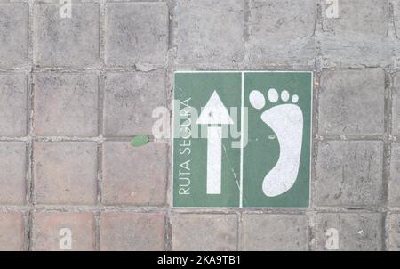 Straßenschild mit einem weißen Pfeil und einem grünen Fuß, das die Richtung der sicheren Route für Fußgänger anzeigt Stockfoto