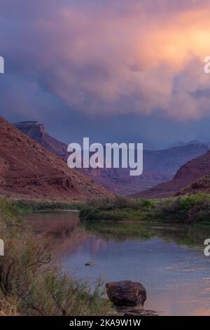 Farbenfrohe Sturmwolken bei Sonnenuntergang über den Fisher Towers und dem Colorado River in der Nähe von Moab, Utah. Stockfoto