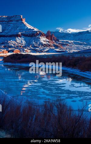 Fisher Towers über dem eisigen Colorado River bei Sonnenuntergang im Winter mit den La Sal Mountains dahinter. In Der Nähe Von Moab, Utah. Stockfoto