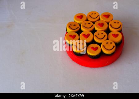 Kleine Kuchen auf dem Teller mit Smiley und Herd zum Feiern Stockfoto