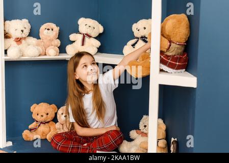 Ein kleines Mädchen wählt in einem Weihnachtsgeschäft Teddybären aus. Weihnachtskarte. Stockfoto