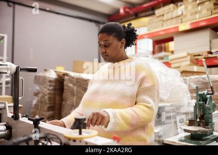 Porträt einer Frau, die in der Druckerei arbeitet und industrielle Druckmaschine, Kopierraum betreibt Stockfoto