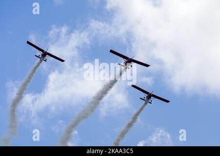 Liepaja, Lettland - 7. August 2022: Drei rote Sportflugzeuge mit Rauchstreifen machen während der Baltic International Airshow einen Aerobatic-Gruppenflug Stockfoto