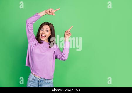 Portrait Foto von jungen attraktiven verrückten Mädchen Regie Finger leeren Raum unerwartete Nachrichten auf grünem Hintergrund isoliert Stockfoto