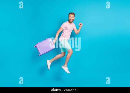 Ganzkörper-Foto von attraktiven jungen Kerl aufgeregt Laufen springen Abfahrt gekleidet stilvolle rosa Look isoliert auf aquamarinfarbenem Hintergrund Stockfoto