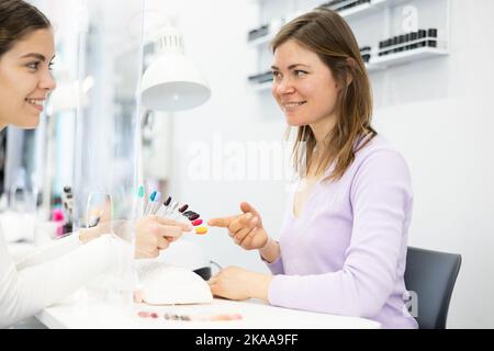 Client Girl wählt einen Nagellack auf einer Farbpalette Stockfoto