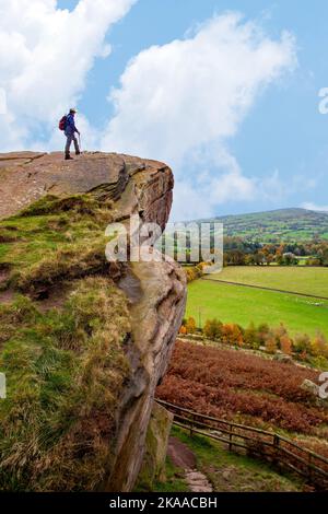 Mann, der auf dem Felsen steht, rast den Hanging Stone in der Landschaft von Ceshire bei Danebridge Ceshire aus Stockfoto