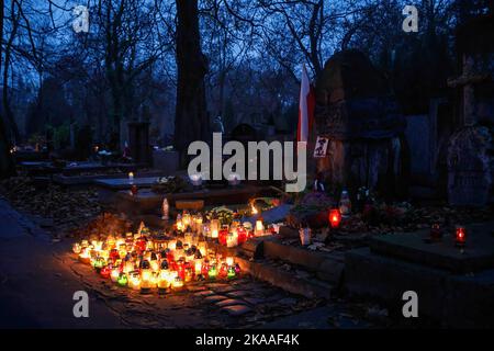 Warschau, Polen. 01.. November 2022. Am Grab des Pow?zki Friedhofs am Allerheiligen sind viele brennende Kerzen und eine polnische Flagge zu sehen. Allerheiligen/Allerseelen (oder Dzie? Zaduszny auf Polnisch) ist ein Feiertag und eine Gelegenheit, an die Toten zu erinnern. An diesem Tag bringen Menschen Blumen und Kerzen auf Friedhofs. In der Dunkelheit ist der Friedhof voller Lichter. Der POW?zki Friedhof (oder Old Pow?zki) ist eine historische Nekropole in Warschau. Es ist der berühmteste Friedhof der Stadt und einer der ältesten. Kredit: SOPA Images Limited/Alamy Live Nachrichten Stockfoto