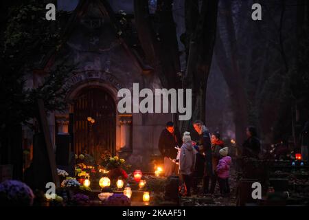 Warschau, Polen. 01.. November 2022. Eine Familie zündet am Allerheiligen-Tag auf dem Pow?zki Friedhof Kerzen an. Allerheiligen/Allerseelen (oder Dzie? Zaduszny auf Polnisch) ist ein Feiertag und eine Gelegenheit, an die Toten zu erinnern. An diesem Tag bringen Menschen Blumen und Kerzen auf Friedhofs. In der Dunkelheit ist der Friedhof voller Lichter. Der POW?zki Friedhof (oder Old Pow?zki) ist eine historische Nekropole in Warschau. Es ist der berühmteste Friedhof der Stadt und einer der ältesten. Kredit: SOPA Images Limited/Alamy Live Nachrichten Stockfoto