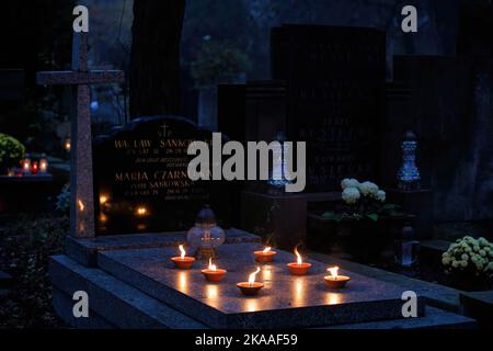 Warschau, Polen. 01.. November 2022. Brennende Kerzen, die am Allerheiligen-Tag auf dem Pow?zki Friedhof auf einem Grab aufgestellt wurden. Allerheiligen/Allerseelen (oder Dzie? Zaduszny auf Polnisch) ist ein Feiertag und eine Gelegenheit, an die Toten zu erinnern. An diesem Tag bringen Menschen Blumen und Kerzen auf Friedhofs. In der Dunkelheit ist der Friedhof voller Lichter. Der POW?zki Friedhof (oder Old Pow?zki) ist eine historische Nekropole in Warschau. Es ist der berühmteste Friedhof der Stadt und einer der ältesten. Kredit: SOPA Images Limited/Alamy Live Nachrichten Stockfoto