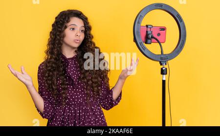 Erstauntes Kind mit langen lockigen Haaren, das Video für Blog macht Stockfoto
