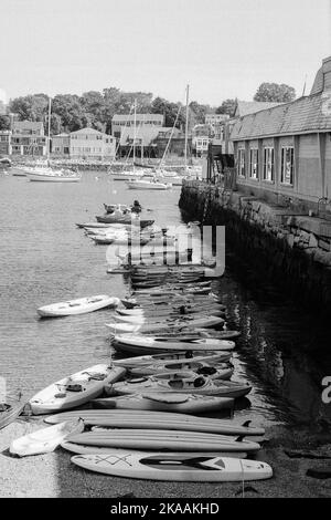 Eine lange Reihe von Kajaks ankerte im Wasser entlang eines Piers in Rockport, Massachusetts. Das Bild wurde auf analogem Schwarzweiß-Film aufgenommen. Stockfoto