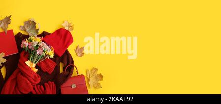 Stilvolle weibliche Kleidung und Accessoires mit Blumenstrauß und Herbstblättern auf gelbem Hintergrund mit Platz für Text Stockfoto