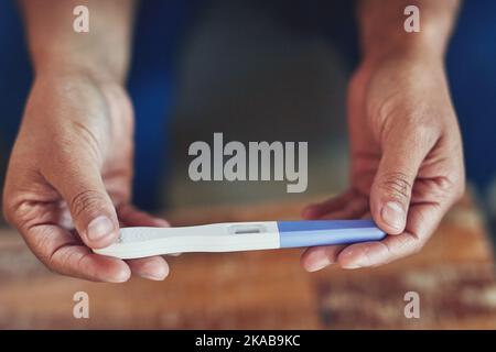 Was wird der Test zeigen. Aufnahme einer nicht identifizierbaren Frau, die zu Hause einen Schwangerschaftstest abnimmt. Stockfoto