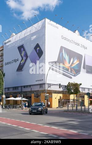 Straßenszene in der Kantstraße in Berlin. Im Hintergrund auf einer Baustelle Werbung für ein Smartphone. Stockfoto