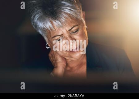 Stress ist ein hoher Preis für den Erfolg. Eine reife Geschäftsfrau erleben Belastung während einer späten Nacht bei der Arbeit. Stockfoto