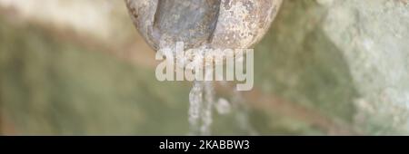 Ein alter alter Steinwasserfall gießt Wasser aus der Nähe Stockfoto