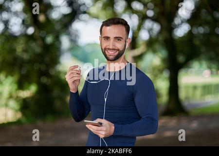 Das beste Projekt, an dem Sie je arbeiten werden, sind Sie. Beschnittenes Porträt eines hübschen jungen männlichen Läufers, der seine Nachrichten während seines Trainings überprüft. Stockfoto