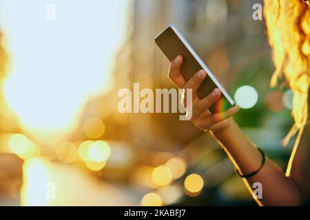 In der Stadt in Verbindung bleiben. Eine nicht erkennbare junge Frau, die einen Text sendet, während sie durch die Stadt läuft. Stockfoto