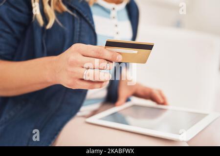 Online-Einkäufe zu tätigen war noch nie so einfach. Nahaufnahme einer Frau, die zu Hause eine Kreditkartenzahlung auf einem digitalen Tablet macht. Stockfoto