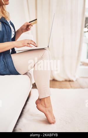 Shopping für einige gute Angebote online. Nahaufnahme einer Frau, die zu Hause eine Kreditkartenzahlung auf einem Laptop macht. Stockfoto