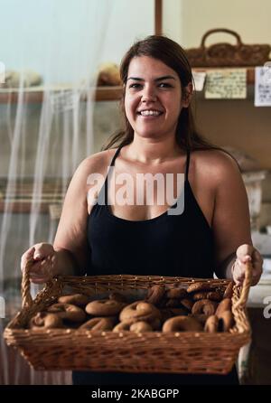 Sie sind frisch aus dem Ofen. Eine junge Frau, die in ihrer Bäckerei arbeitet. Stockfoto
