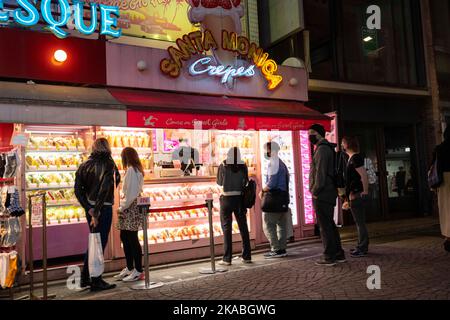 Tokio, Japan. 1.. November 2022. Ein Crepe-Stand von Santa Monica in der Takeshita Street (ç«¹ä¸‹é€šã‚Š)am Abend in Harajuku (åŽŸå®¿), einem Viertel, das für Süßigkeiten, Kawaii-Kultur, Cosplay, schnelle Mode und allgemeine Niedlichkeit bekannt ist. Japan hat kürzlich nach mehr als zwei Jahren Reiseverbote aufgrund der COVID-19-Pandemie wieder für den Tourismus geöffnet. Der Yen hat gegenüber dem US-Dollar stark abgeschrieben, was wirtschaftliche Turbulenzen für den internationalen Handel und die japanische Wirtschaft verursacht hat. Touristen können in Japan steuerfrei mit einem temporären Besuchervisum einkaufen. (Bild: © Taidgh Barron/ZUMA Press Wire) Stockfoto