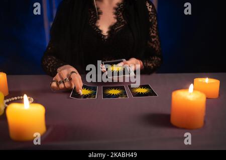 Tarot-Leser Kommissionierung Tarot-Karten in der Nähe brennende Kerzen.Kerzenlicht im Dunkeln.Tarot-Leser oder Wahrsager Lesung und Prognose Konzept. Stockfoto