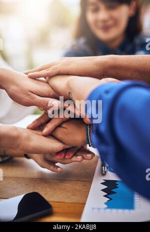 Wir sind die Bausteine des Geschäfts. Eine Gruppe von unkenntlichen Völkern Hände bilden einen Huddle zusammen um einen Tisch draußen. Stockfoto