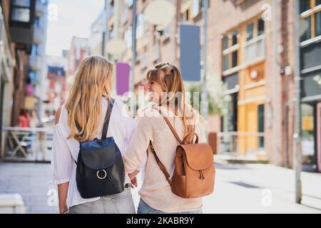 Mädchen in der Stadt. Rückansicht von zwei attraktiven jungen Freundinnen, die eine fremde Stadt erkunden. Stockfoto