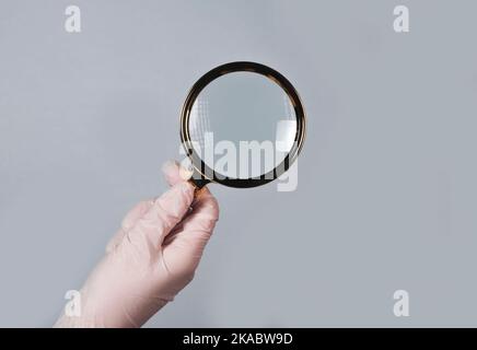 Hand in Hand halten Sie die Lupe, um Krankheiten mit optischem Glas zu finden und zu untersuchen. Stockfoto