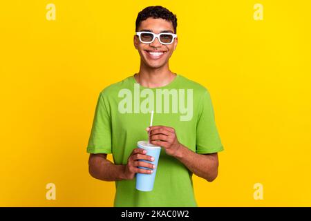 Porttrait Foto von jungen positiv attraktiv lächelnden Mann tragen weiße Gläser gute Laune halten Soda Cola trinken Emotion nach Kino isoliert auf gelb Stockfoto