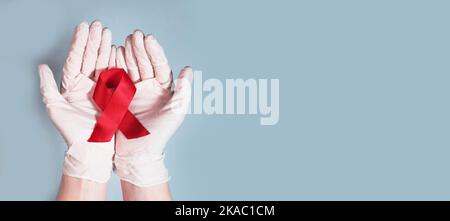 Roter Bandbogen für AIDS und HIV-Bewusstsein in den Händen. Medizinisches Banner mit Kopierbereich. Stockfoto