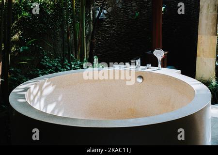 Abgerundete Badewanne aus Beton mit Terrazzo-Finish. Es wird in einer Villa in Ubud, Bali, verwendet Stockfoto