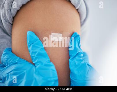 Hände, Gips und Arm in Covid-Impfstoff zur Injektion, Heilung oder Jab bei Arzttermin durch das Krankenhaus. Hand des Gesundheitsdienstleistenden GP, der Verband anführt Stockfoto