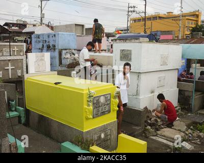 Caloocan City, Philippinen. 01.. November 2022. Die Besucher des Friedhofs verbringen während Allerheiligen Zeit in den Gräbern ihrer Lieben. Filipinos strömen nach zwei Jahren der Covid-19-Pandemie auf Friedhofs, da sich die Einschränkungen langsam lockern. Die Tradition, Blumen zu bringen, Kerzen anzuzünden und sogar Nahrung an der Begräbnisstätte ihrer verstorbenen Lieben anzubieten. Kredit: SOPA Images Limited/Alamy Live Nachrichten Stockfoto