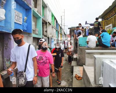 Caloocan City, Philippinen. 01.. November 2022. Friedhofsbesucher spazieren während des Allerheiligen-Tages durch enge Nischen. Filipinos strömen nach zwei Jahren der Covid-19-Pandemie auf Friedhofs, da sich die Einschränkungen langsam lockern. Die Tradition, Blumen zu bringen, Kerzen anzuzünden und sogar Nahrung an der Begräbnisstätte ihrer verstorbenen Lieben anzubieten. Kredit: SOPA Images Limited/Alamy Live Nachrichten Stockfoto