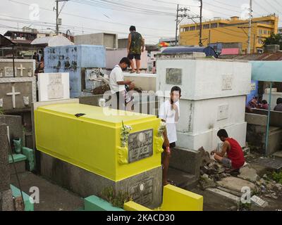 Caloocan City, Philippinen. 01.. November 2022. Die Besucher des Friedhofs verbringen während Allerheiligen Zeit in den Gräbern ihrer Lieben. Filipinos strömen nach zwei Jahren der Covid-19-Pandemie auf Friedhofs, da sich die Einschränkungen langsam lockern. Die Tradition, Blumen zu bringen, Kerzen anzuzünden und sogar Nahrung an der Begräbnisstätte ihrer verstorbenen Lieben anzubieten. (Foto: Josefiel Rivera/SOPA Images/Sipa USA) Quelle: SIPA USA/Alamy Live News Stockfoto