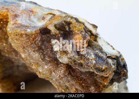 Glänzender echter roher Achatblock, brauner, gelber und weißer Achatchalcedon mit Achatdruse und kleinen Kristallsteinpunkten Makronah isoliert Stockfoto