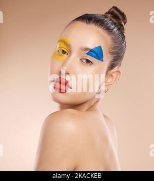 Schönheit, Make-up und Clown von Frau im Studio für Spaß, Kunst und kreativen Ausdruck vor einem braunen Hintergrund mit Mockup. Gesicht, Porträt und Pigment Stockfoto