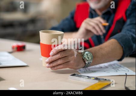 Nahaufnahme eines Mans Hand mit einem Papierbecher Stockfoto
