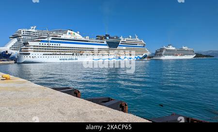 Riesige Kreuzfahrtschiffe, die in Korfu Griechenland vor Anker liegen, zeigen deutlich die unterschiedlichen Größen der Schiffe, die durch die Ozeane und Meere fahren Stockfoto